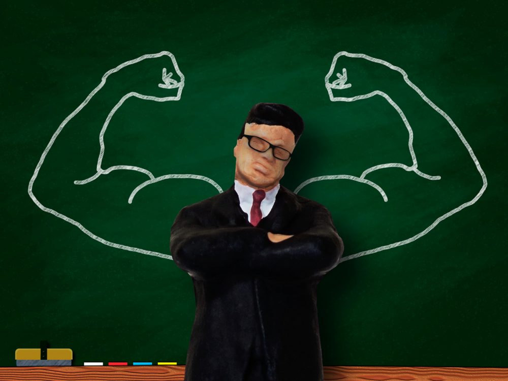 黒板に描いた筋肉質の上腕とビジネスマン模型